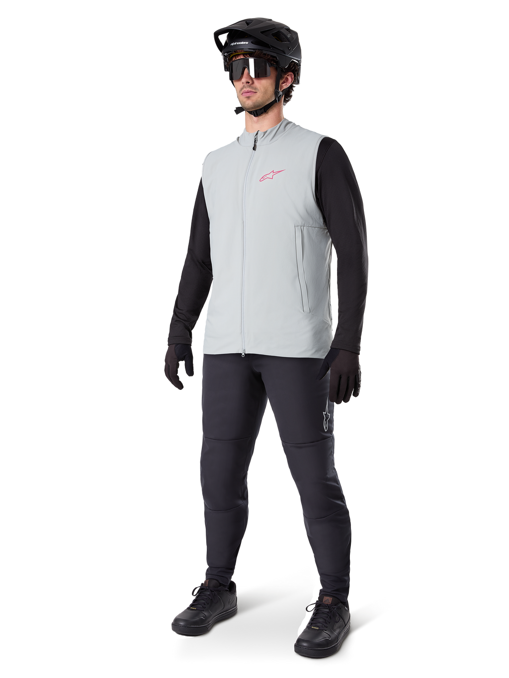 Alpinestars A-Dura Thermoweste, Radweste in Titanium-Grau mit pinkem Logo, getragen von einem Modell mit schwarzem Langarmshirt, dunkelgrauer Hose und schwarzem Mountainbike-Helm, Performance-Ausrüstung für Fahrten bei kaltem Wetter