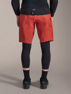 Alpinestars A-Motion Plasma Knie-Sleeve, schwarze MTB-Knieschützer, Rückansicht getragen unter roten Mountainbike-Shorts mit schwarzem Trikot und technischen Radschuhen, Schutzausrüstung für das Mountainbiken