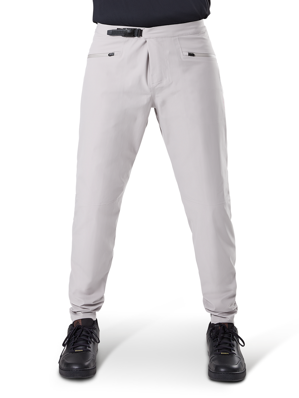 Alpinestars A-Dura Wasserdichte Hose, MTB-Radhose, Titanium-Grau, Vorderansicht, mit schwarzem Ratschenverschluss an der Taille und zwei Reißverschlusstaschen, elastische Bündchen, getragen mit schwarzen Sneakern, technische wasserdichte Ausrüstung zum Mountainbiken