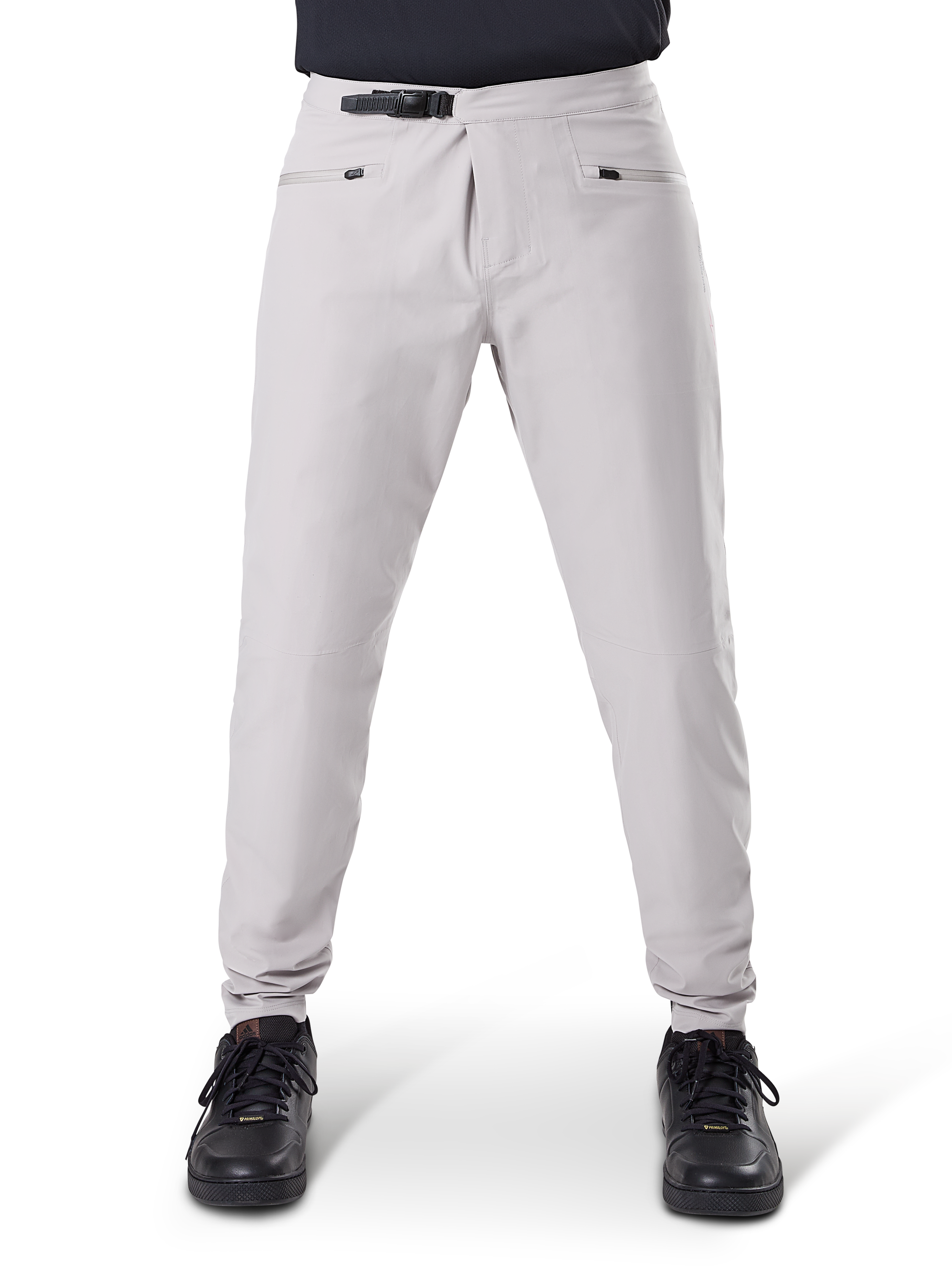 Alpinestars A-Dura Wasserdichte Hose, MTB-Radhose, Titanium-Grau, Vorderansicht, mit schwarzem Ratschenverschluss an der Taille und zwei Reißverschlusstaschen, elastische Bündchen, getragen mit schwarzen Sneakern, technische wasserdichte Ausrüstung zum Mountainbiken