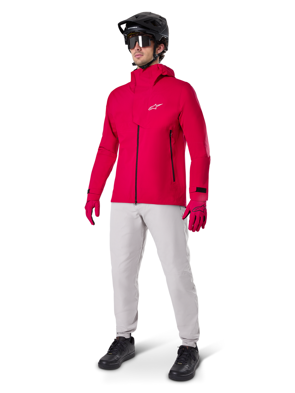 Modell trägt Alpinestars A-Dura wasserdichte Hose in Titanium-Grau, kombiniert mit einer leuchtend roten wasserdichten Jacke und passenden Handschuhen, einem schwarzen Mountainbike-Helm mit Goggles und schwarzen Schuhen, komplette Mountainbike-Ausrüstung für nasse Trail-Bedingungen