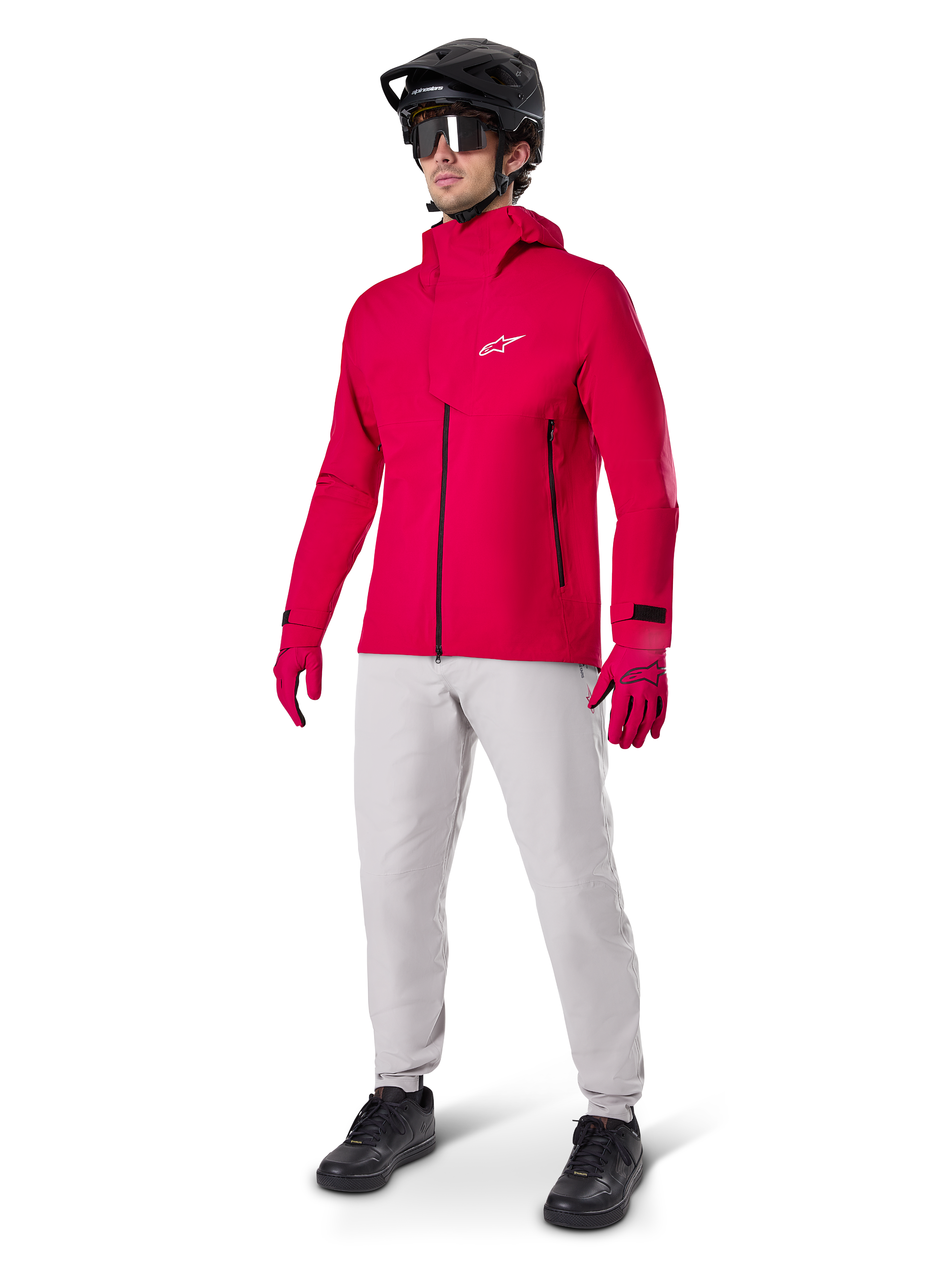 Modell trägt Alpinestars A-Dura wasserdichte Hose in Titanium-Grau, kombiniert mit einer leuchtend roten wasserdichten Jacke und passenden Handschuhen, einem schwarzen Mountainbike-Helm mit Goggles und schwarzen Schuhen, komplette Mountainbike-Ausrüstung für nasse Trail-Bedingungen