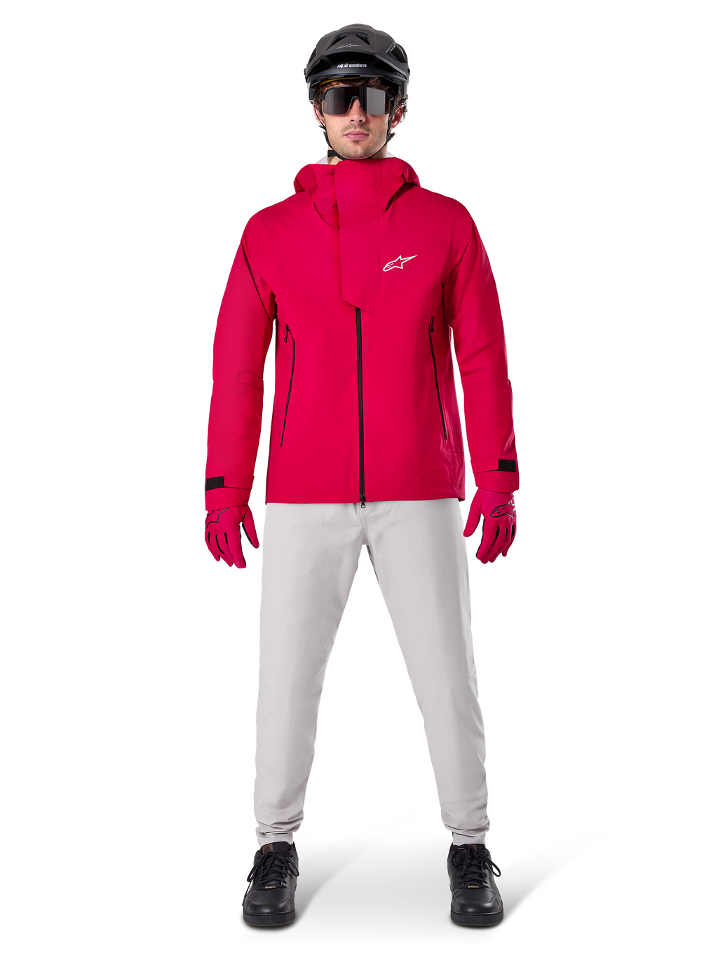 Alpinestars A-Dura Wasserdichte Hose, MTB-Hose, Titanium-Grau, getragen mit einer leuchtend roten Kapuzenjacke, roten Handschuhen und einem schwarzen Mountainbike-Helm, professionelle wasserdichte Fahrradausrüstung für nasse Trail-Bedingungen