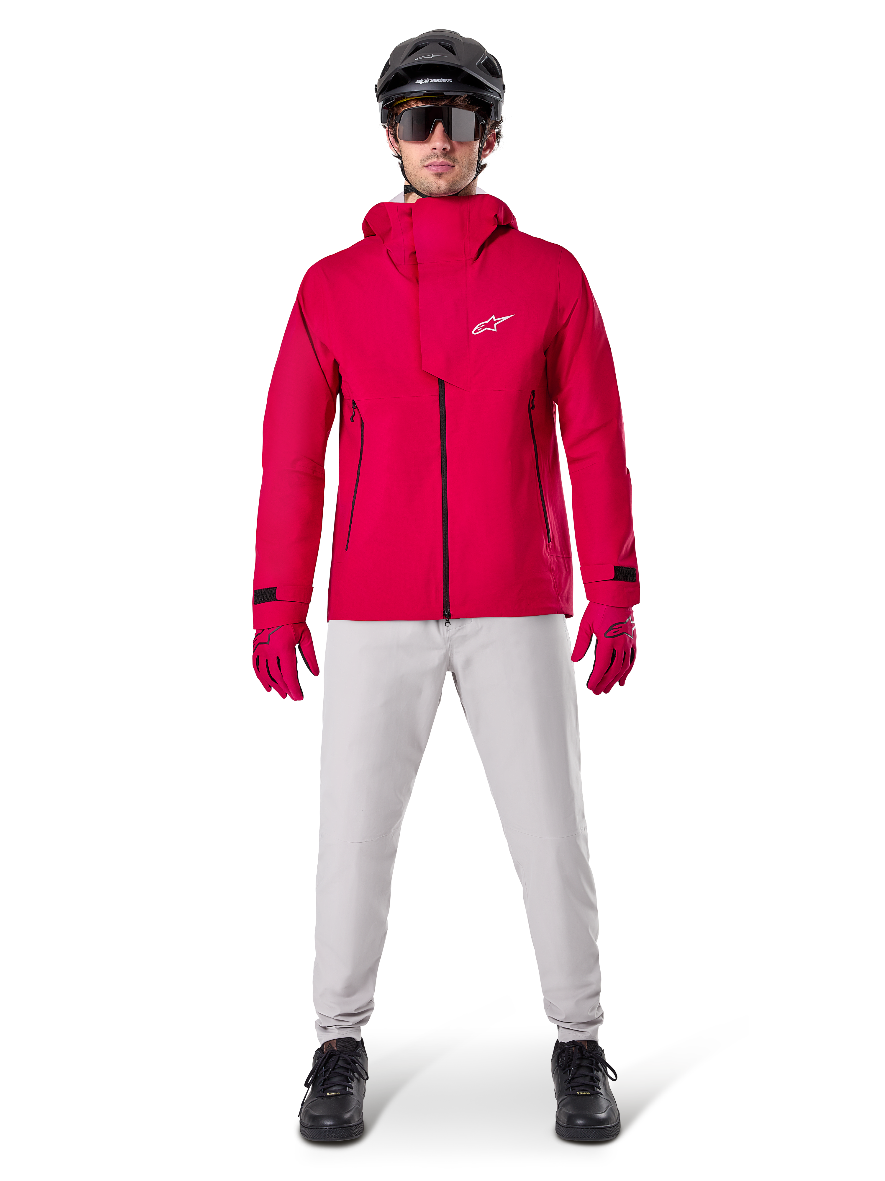 Alpinestars A-Dura Wasserdichte Hose, MTB-Hose, Titanium-Grau, getragen mit einer leuchtend roten Kapuzenjacke, roten Handschuhen und einem schwarzen Mountainbike-Helm, professionelle wasserdichte Fahrradausrüstung für nasse Trail-Bedingungen
