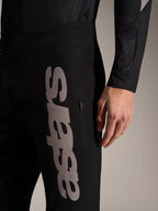 Schwarze A-Supra Elite Hose mit großem grauen vertikalen Astars-Schriftzug und Reißverschlusstasche für MTB-Rennen.
