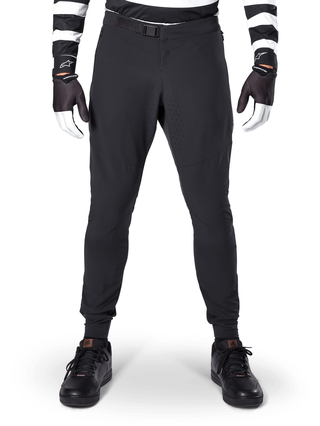 Alpinestars A-Aria Elite Pants, Mountain Bike Pants, Black, front view showing laser perforations and magnetic buckle closure, worn with a black and white striped jersey and black gloves, performance cycling gear for trail riding