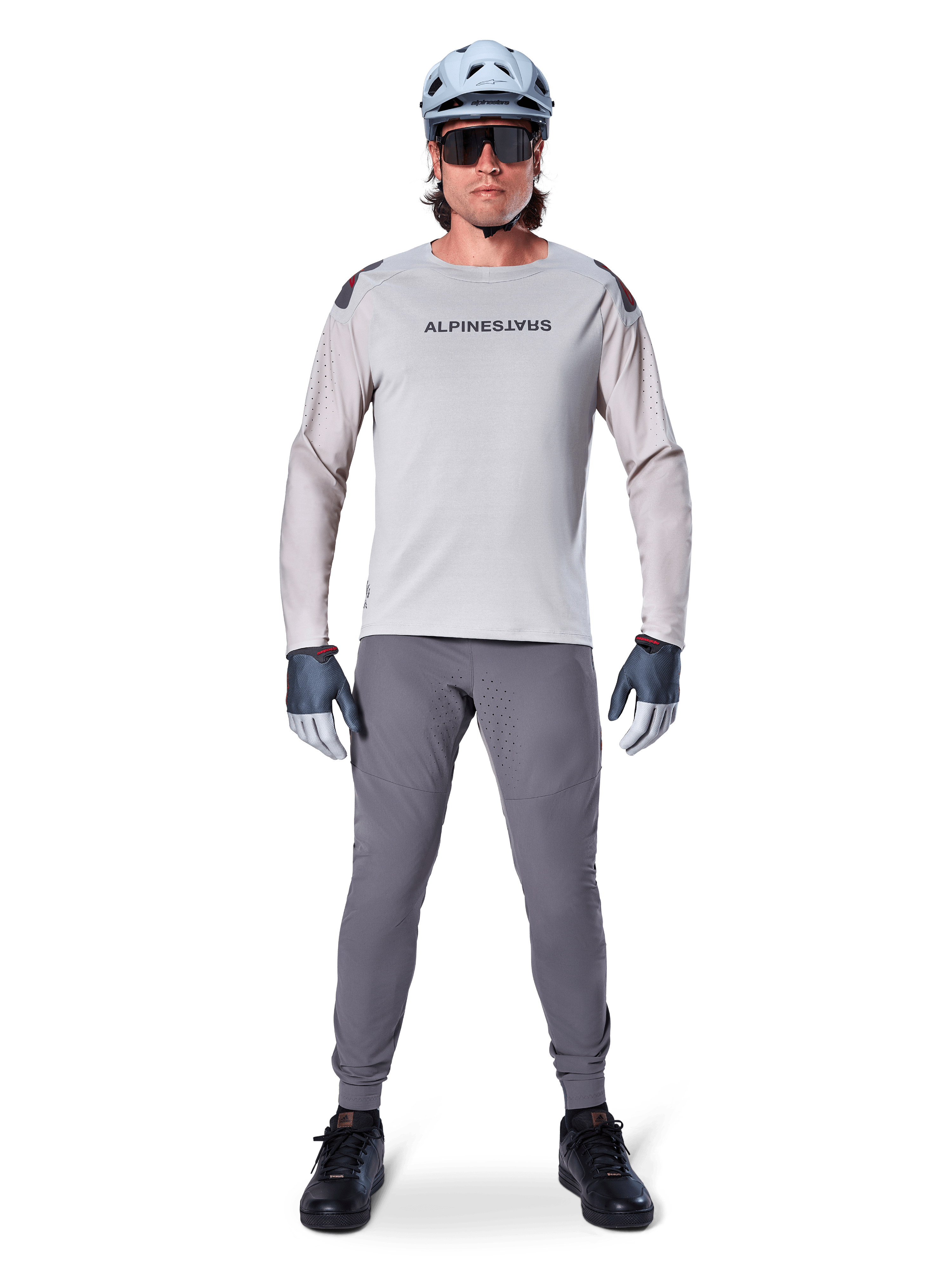 Alpinestars A-Aria Elite Pants, Dark Gray Mountain Bike Pants, worn by a rider in a light gray long-sleeve jersey, light blue helmet, and black shoes, featuring visible laser perforations on the inner legs and a slim performance fit.