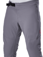 Alpinestars A-Aria Elite Pants, MTB Cycling Pants, Dark Gray, close-up view featuring the magnetic buckle closure, zippered side pocket, and laser-cut ventilation perforations on the inner thighs for trail riding performance.