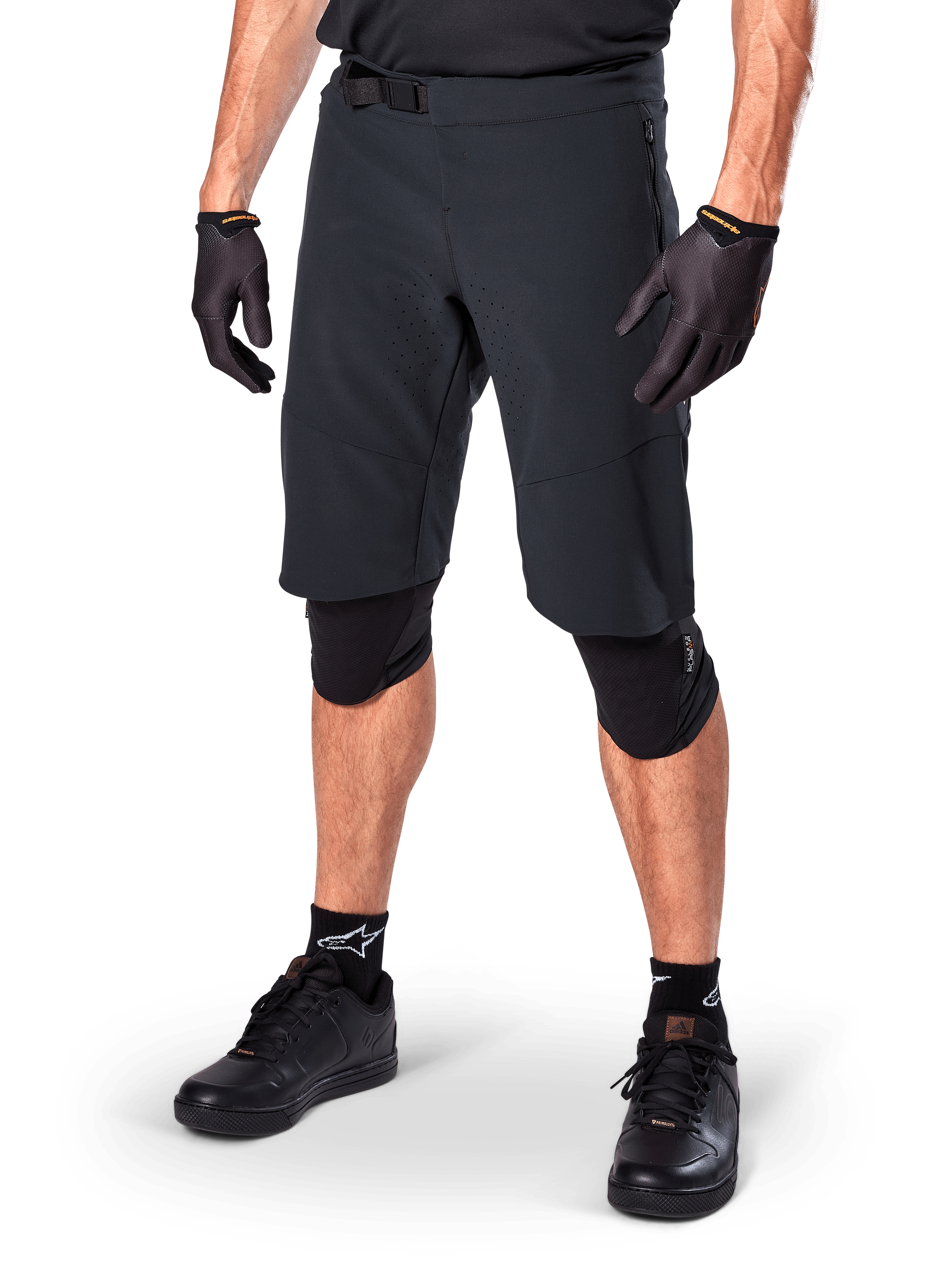 Alpinestars A-Aria Elite Shorts, schwarze Radsport-Shorts, getragen mit passenden schwarzen Handschuhen und Knieschützern, mit Magnetschnalle und lasergeschnittenen Perforationen, schlankes Design für Offroad-Mountainbiking