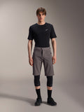 Alpinestars A-Dura Elite Shorts, Dark Gray Mountain Bike Shorts, worn with a black crew neck t-shirt and black knee guards, knee-length performance cycling apparel featuring a front snap closure and durable Cordura fabric.