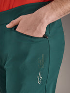 Alpinestars A-Dura Pants in Dark Pine green, close-up of zippered pocket with hand, featuring white Alpinestars logo and text branding on the thigh, durable MTB cycling trousers
