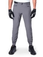 Alpinestars A-Dura Pants, Dark Gray Mountain Bike Pants, front view worn with black gloves and black sneakers, featuring double snap waist closure, zippered hand pockets, and elasticated cuffs, durable cycling apparel for trail riding