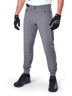 Alpinestars A-Dura Pants, Dark Gray MTB Pants, featuring double snap waist closure and zippered pockets, elasticated cuffs, worn with black cycling gloves and black sneakers