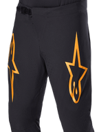 Alpinestars A-Supra Race Pants, Black MTB Cycling Pants with large orange star logos, featuring a front ratchet closure and laser-perforated ventilation holes, performance-oriented technical design.