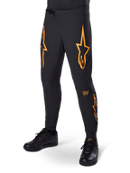 Alpinestars A-Supra Race Pants, Black with orange star graphics, MTB racing pants featuring laser-perforated ventilation and ratchet waist closure, slim performance fit for off-road cycling