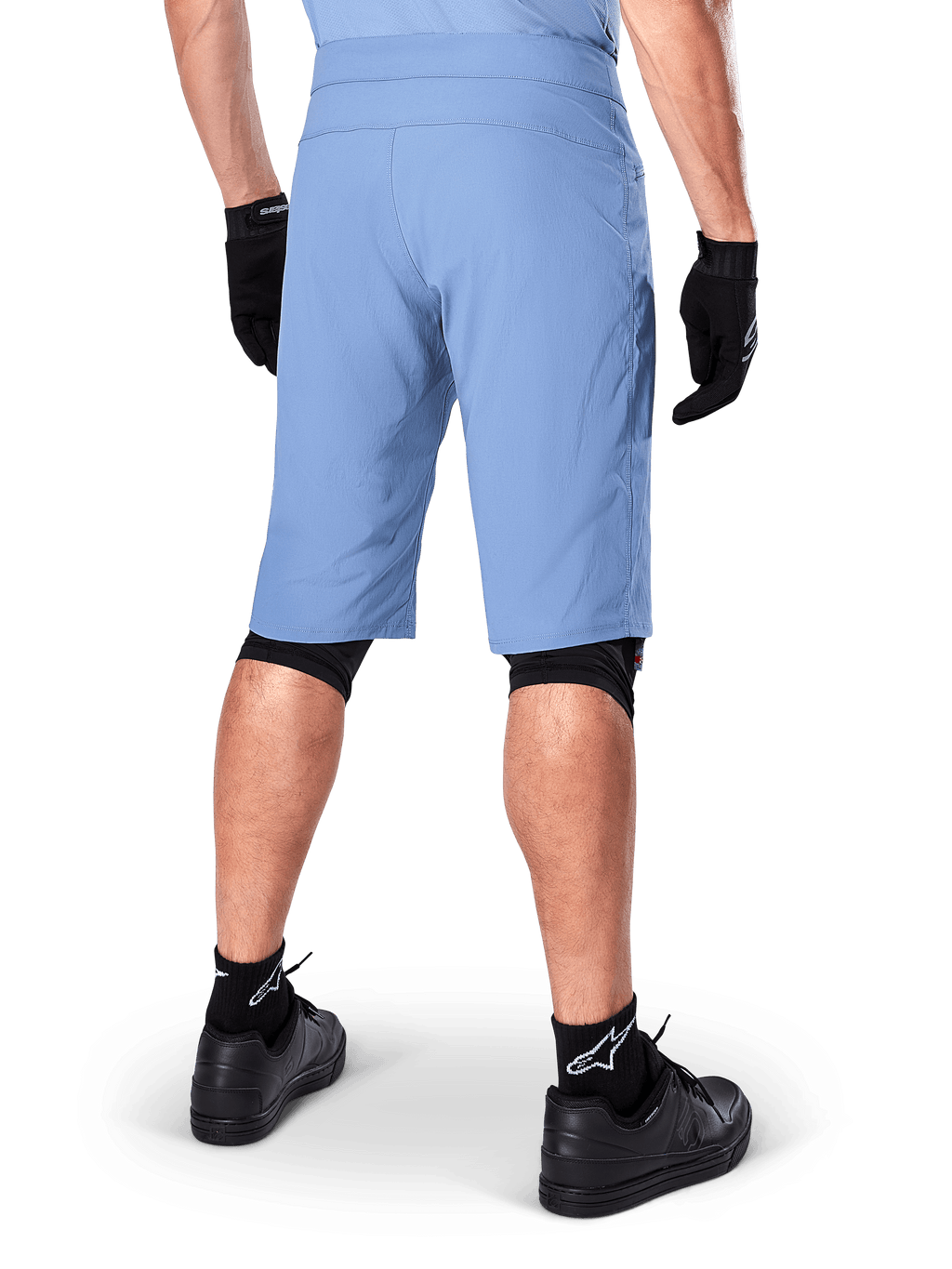 Alpinestars A-Dura Shorts, Mountainbike-Shorts in Infinity Blue, Rückansicht, kombiniert mit schwarzen Handschuhen, Knieschonern und schwarzen Socken mit weißem Stern-Logo, strapazierfähiges Stretch-Material für Offroad-Radsport