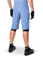 Alpinestars A-Dura Shorts, Mountainbike-Shorts in Infinity Blue, Rückansicht, kombiniert mit schwarzen Handschuhen, Knieschonern und schwarzen Socken mit weißem Stern-Logo, strapazierfähiges Stretch-Material für Offroad-Radsport