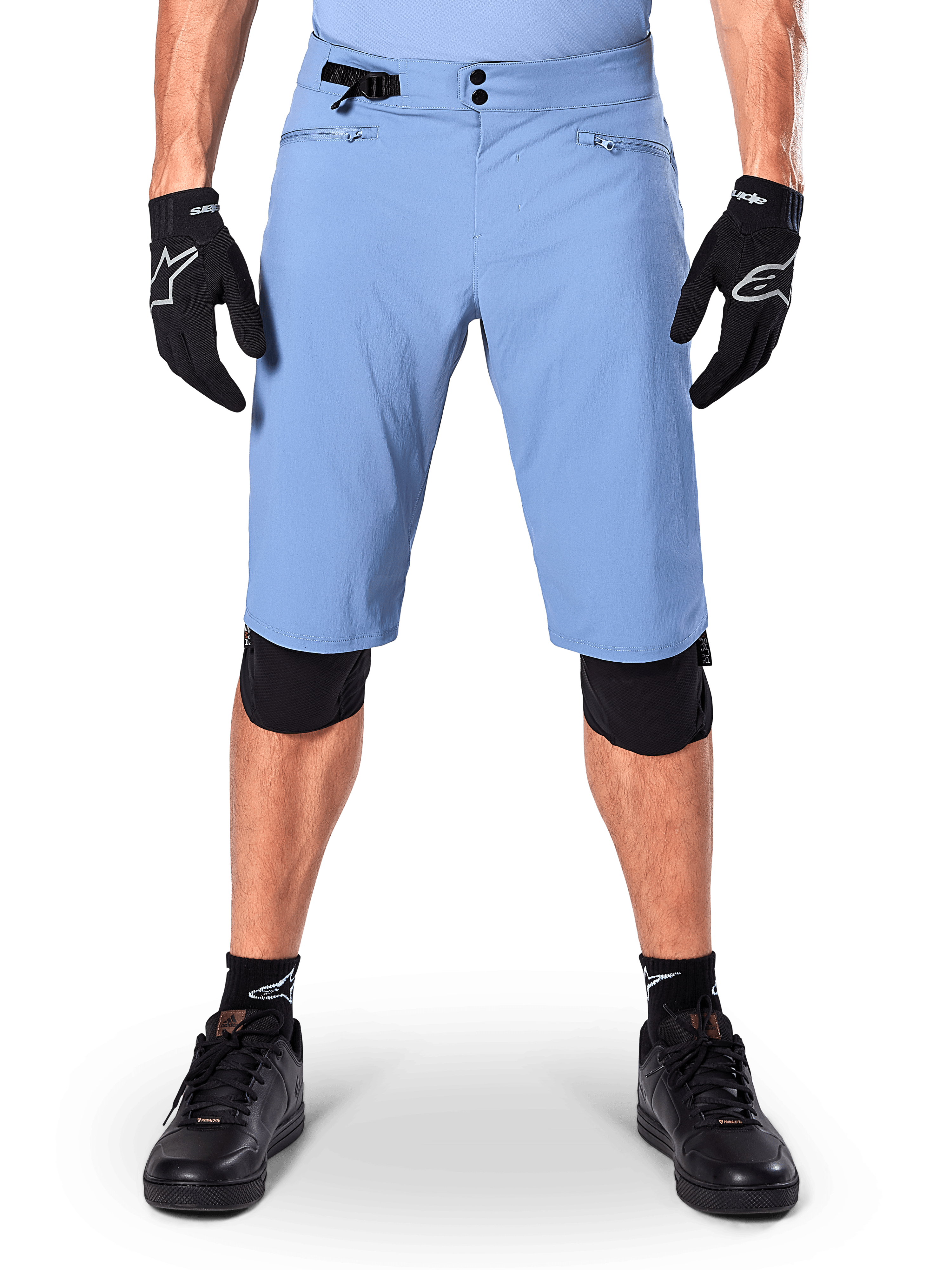 Alpinestars A-Dura Shorts, Mountainbike-Shorts in Infinity Blue, getragen mit schwarzen Handschuhen und Knieschonern, mit doppeltem Druckknopfverschluss und seitlichem Taillenversteller, Performance-MTB-Ausrüstung