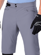Alpinestars A-Dura Shorts, MTB Shorts, Dark Gray, close-up view of waist showing double snap closure, side cinch adjuster, and zippered pockets, paired with black cycling gloves, durable mountain bike apparel.