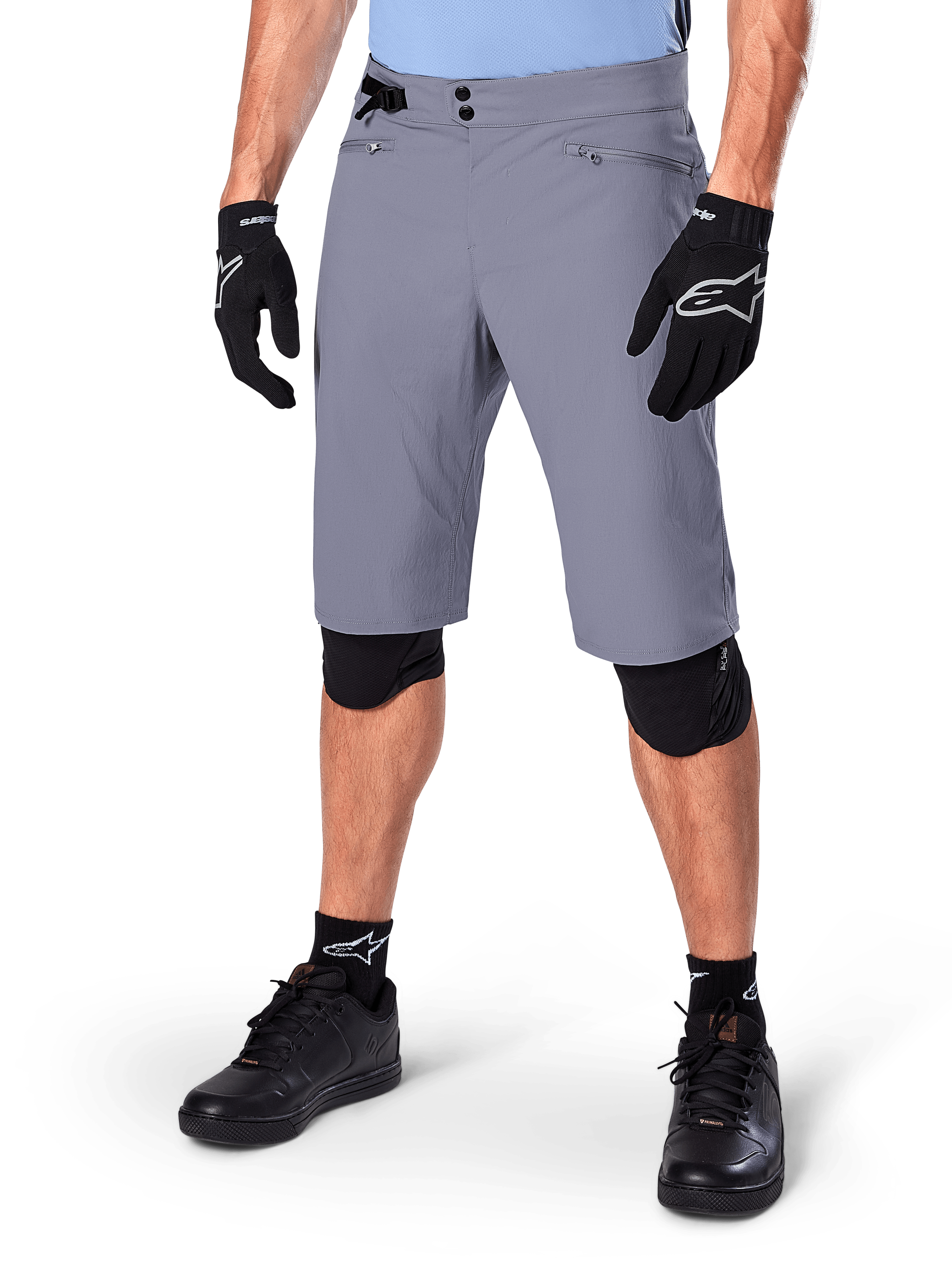 Alpinestars A-Dura Shorts, Dark Gray Mountain Bike Shorts, paired with black gloves and knee guards, featuring zippered pockets and double snap closure, rugged cycling gear for off-road trails