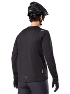 Alpinestars A-Dura Thermal Jersey, long-sleeve mountain bike jersey, Black, back view showing extended drop tail, small reflective details, and hem branding, worn with a black helmet and gloves for cold-weather cycling
