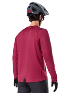 Alpinestars A-Dura Thermal Trikot, Langarm-Mountainbike-Trikot, Burgund, Rückansicht am Model mit grauem MTB-Helm und schwarzen Handschuhen, mit verlängertem Rückenteil und kleinen Logo-Details, entwickelt für Trail-Fahrten bei kaltem Wetter.