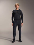 Alpinestars A-Aria Polartec Elite Langarm-Trikot in Schwarz, männliches Model mit weißem Astars-Logo auf der Brust und Branding an den Schultern, kombiniert mit schwarzer technischer MTB-Hose und Schuhen, Performance-Mountainbike-Ausrüstung
