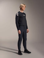Model im Alpinestars A-Aria Polartec Elite Langarm-Trikot in Schwarz, kombiniert mit passender schwarzer technischer Mountainbike-Hose und schwarzen Schuhen, Performance-Radsportbekleidung für Offroad-Fahrten, Studioaufnahme.