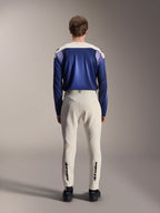 Alpinestars A-Aria Polartec Maker Elite Langarm-Trikot, Baja Blue und Off-White, Rückansicht eines Models in technischer Mountainbike-Ausrüstung, einschließlich cremeweißer Hose mit Alpinestars-Branding an den Unterschenkeln, Performance-Cycling-Outfit für Offroad-Trails