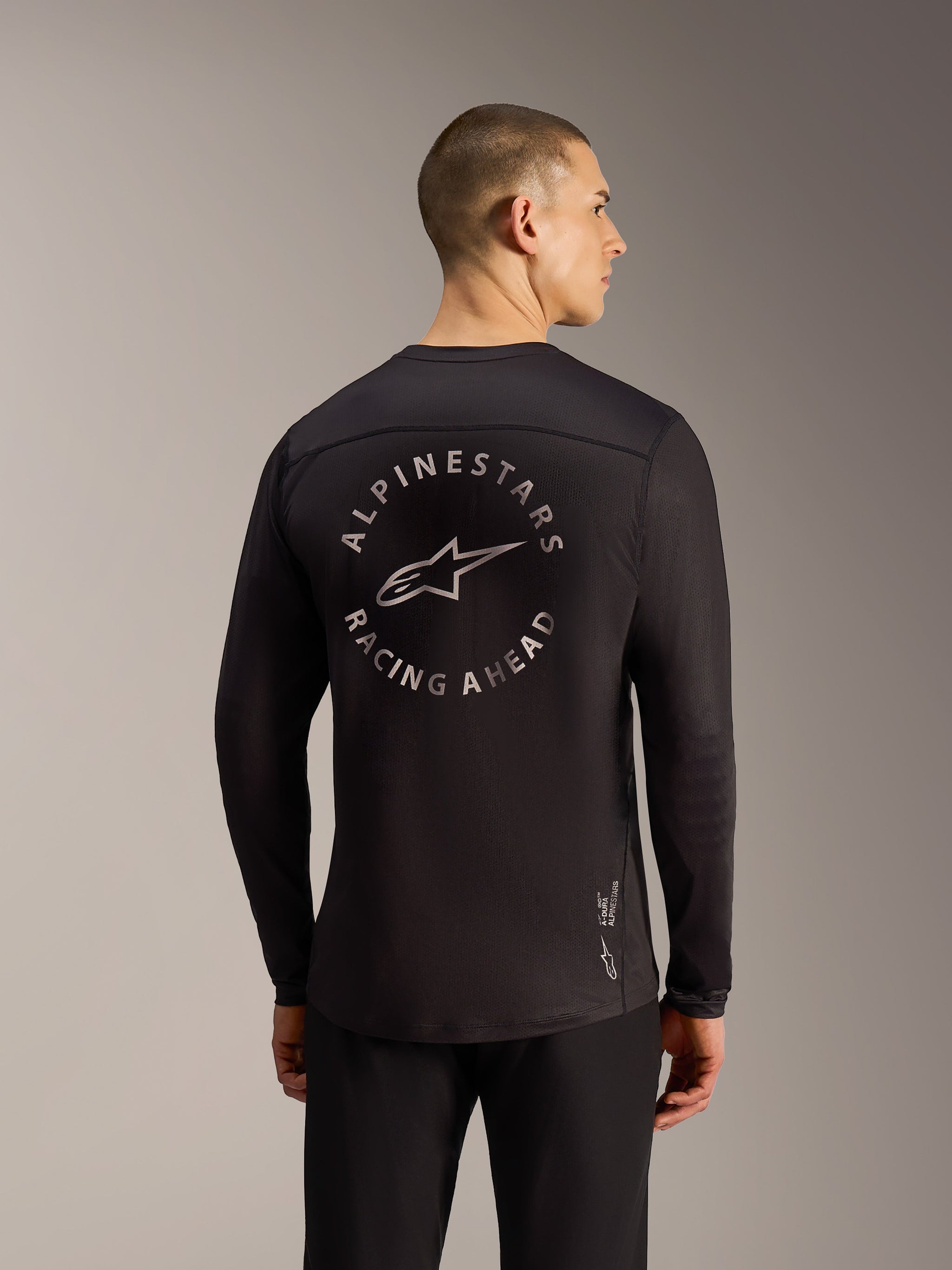 Black A-Dura Air LS Jersey back view featuring a circular Alpinestars Racing Ahead graphic and breathable mesh fabric.