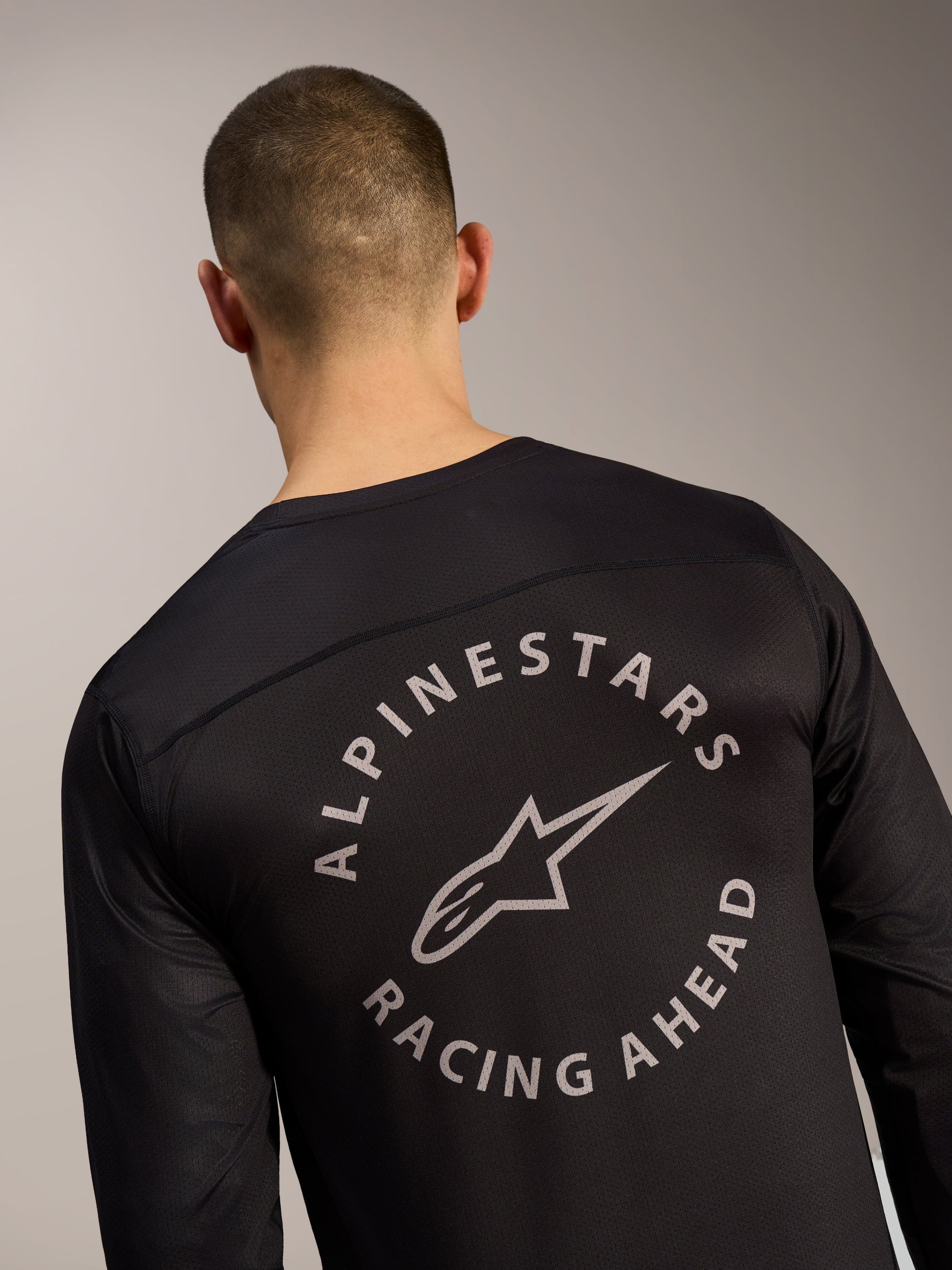 Black A-Dura Air Long Sleeve Jersey back detail, featuring the Alpinestars Racing Ahead circular logo on mesh fabric.