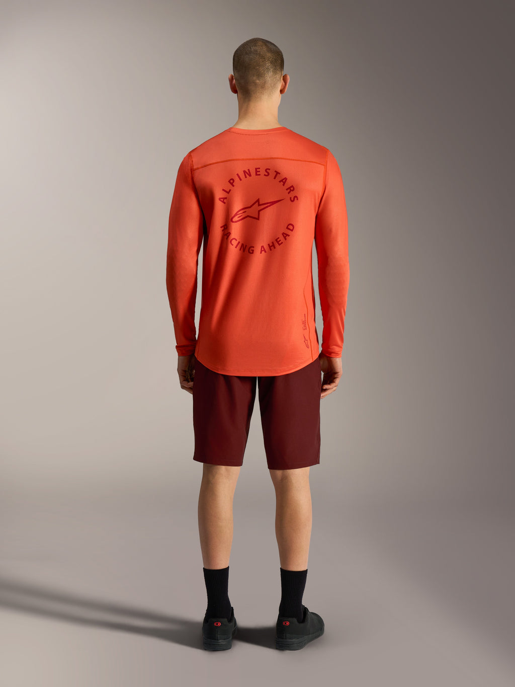 Oranges A-Dura Air LS Jersey und bordeauxrote Ride Shorts, Rückansicht der funktionellen Alpinestars MTB-Bekleidung.