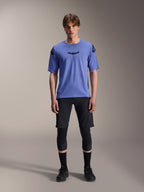 Alpinestars A-Aria Lite Short, Herren-Mountainbike-Shorts, Schwarz, getragen mit hellviolettem Kurzarm-Trikot und schwarzen Knieschonern, Performance-MTB-Bekleidung