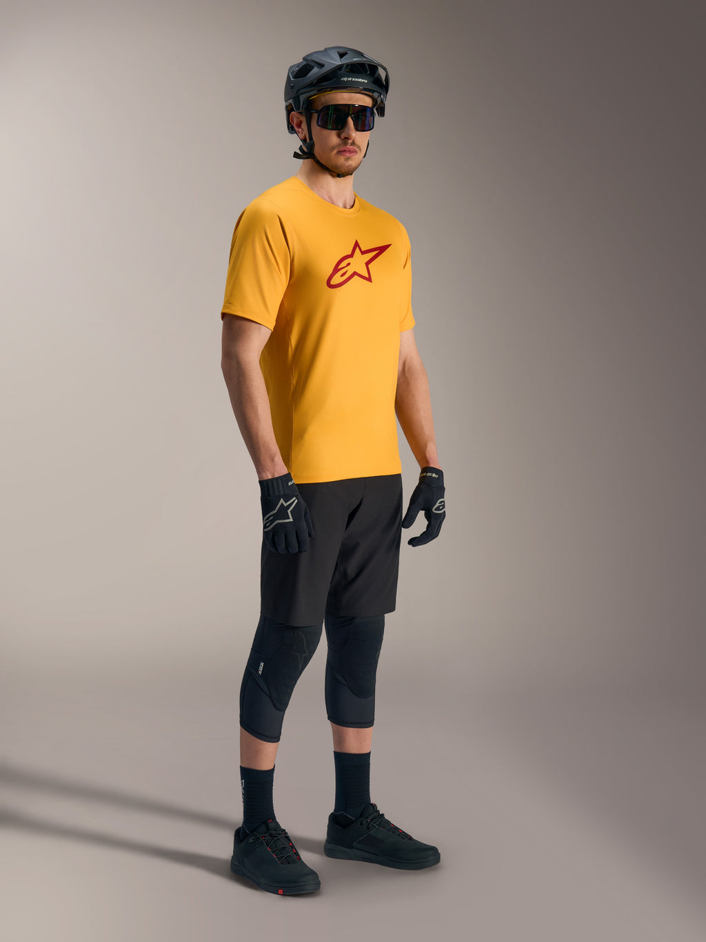 Oranges A-Dura Ride Kurzarmtrikot mit rotem Astars-Logo, kombiniert mit schwarzer MTB-Ausrüstung und Helm.
