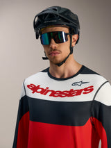 Alpinestars A-Dura Race Langarmtrikot in Rot, Schwarz und Weiß mit Brustlogo, schwarzem MTB-Helm und Goggles.
