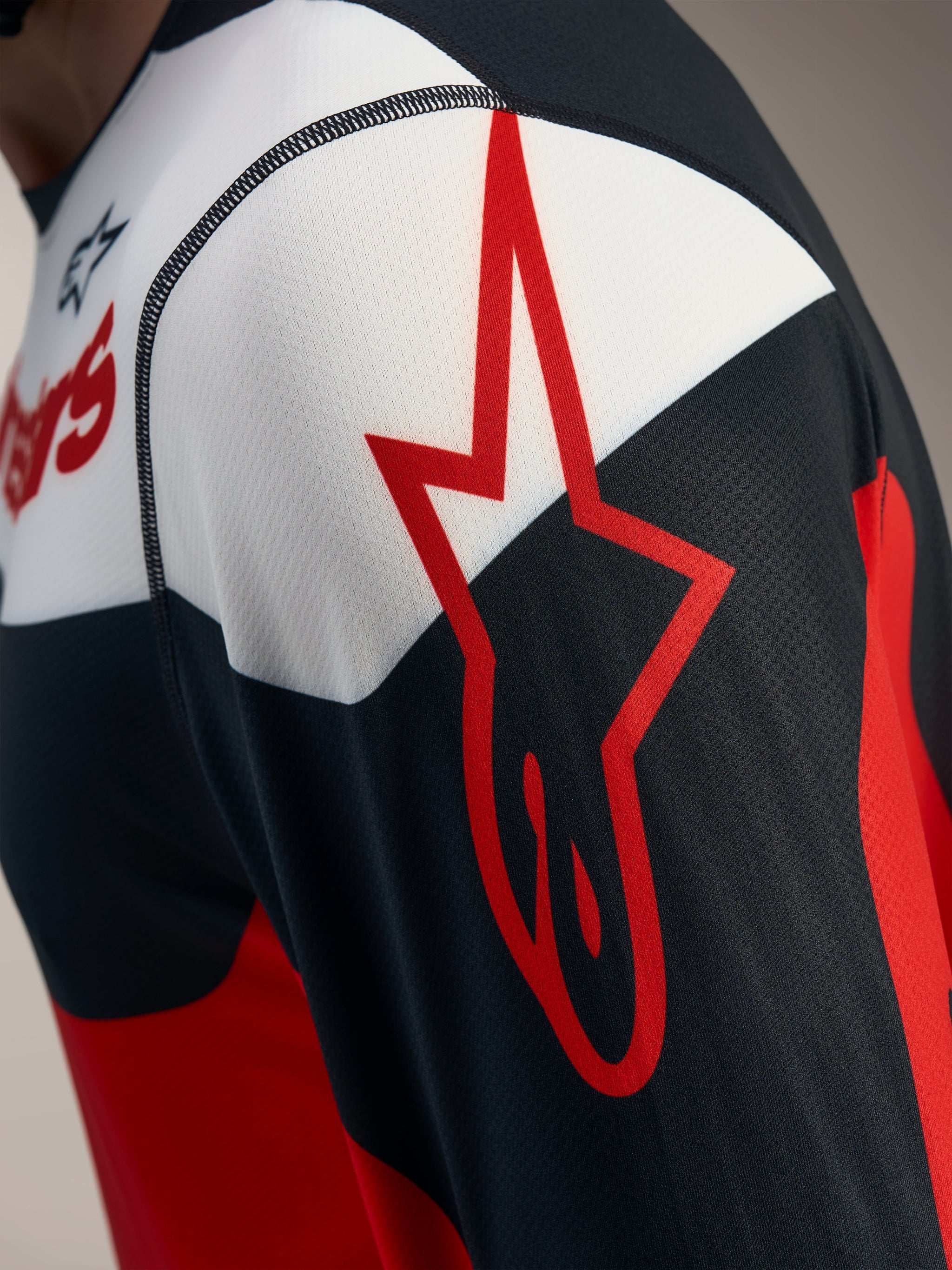 Rot-schwarzes A-Dura Race Langarmtrikot, Detail mit Alpinestars-Sternlogo auf atmungsaktivem Jacquard-Mesh.