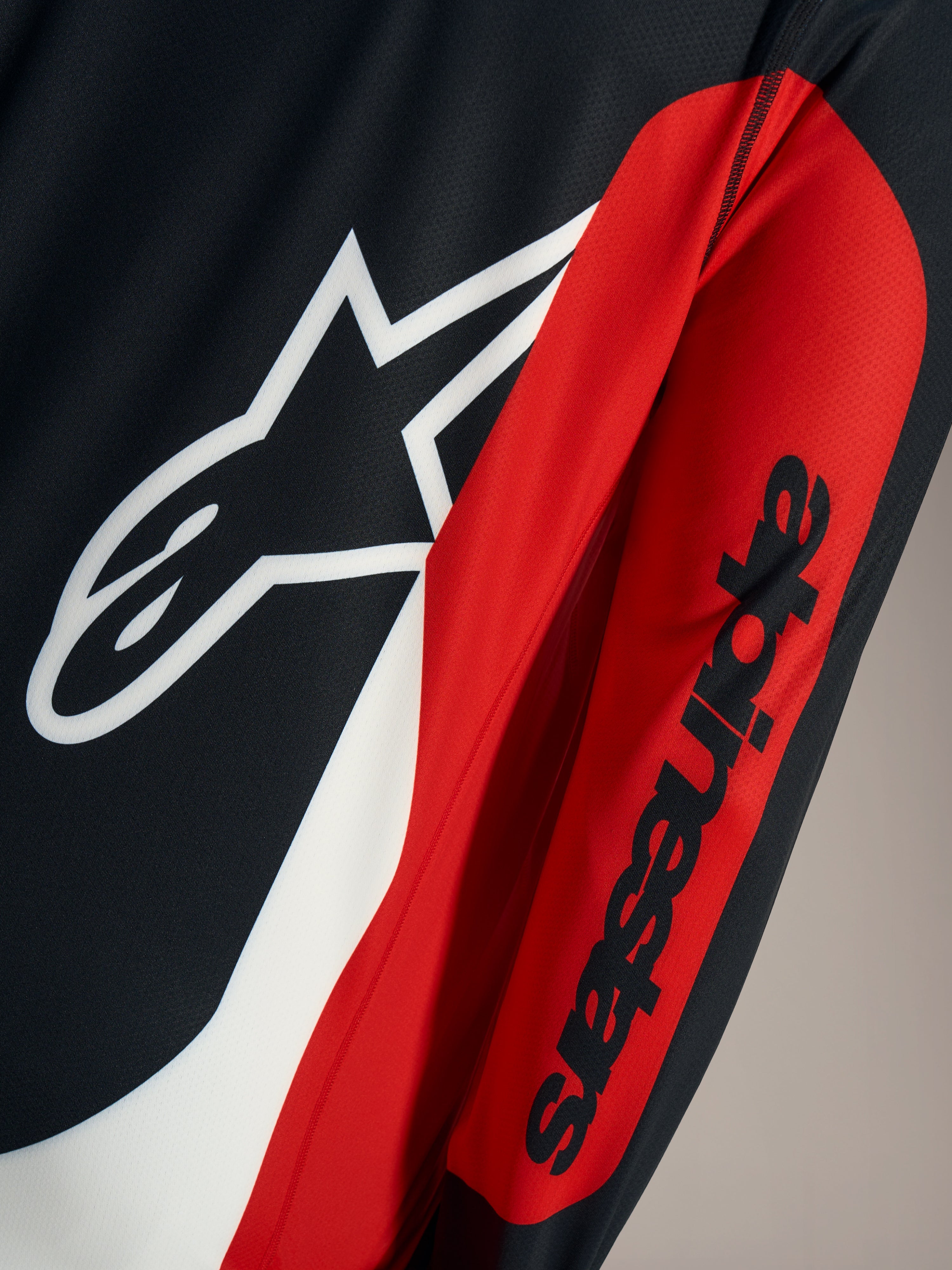 A-Dura Race Trikot-Detail mit weißem Astars-Logo und schwarzem Schriftzug auf rot-schwarzem Mesh-Gewebe.