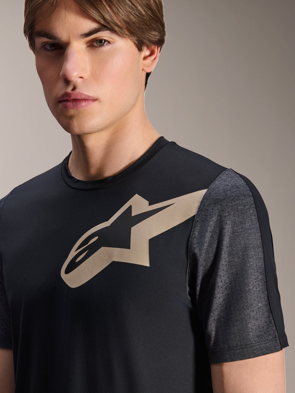 Alpinestars A-Dura Lipan Kurzarmtrikot, Schwarz, mit beigefarbenem Astars-Logo auf der Brust und dunkelgrau melierten, perforierten Ärmeln, Performance-Mountainbike-Bekleidung