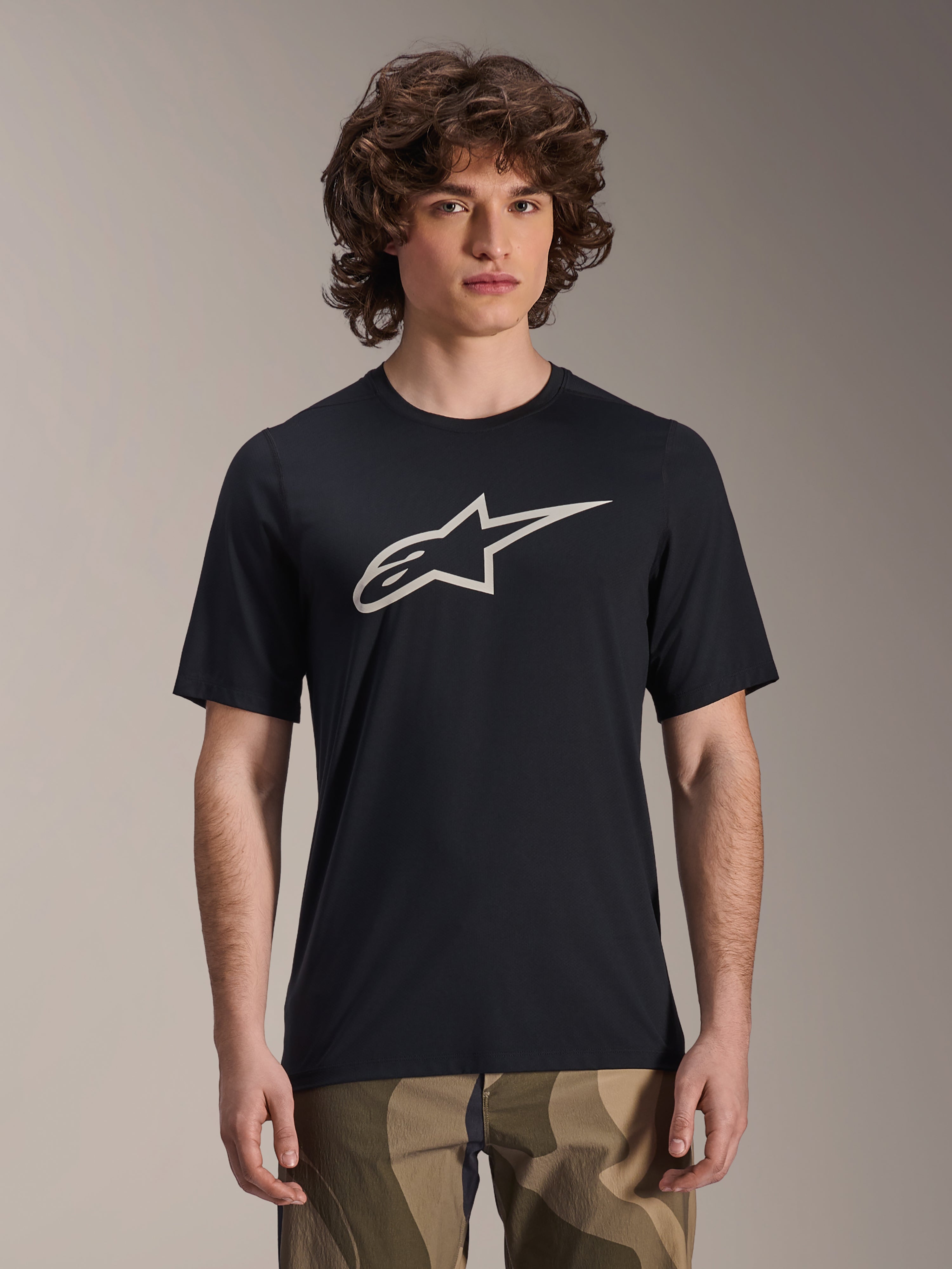 Alpinestars A-Dura Astar Trikot, Kurzarm-MTB-Trikot, Schwarz mit weißem Stern-Logo, getragen mit Camouflage-Hose, lässige Mountainbike-Bekleidung, technisches, feuchtigkeitsableitendes Material