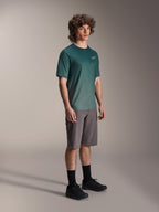 Alpinestars A-Dura Rise Kurzarmtrikot in Silver Pine, grünes Mountainbike-Trikot getragen von einem Model mit grauen Shorts und schwarzen Sneakern, lässige MTB-Trail-Ausrüstung mit kleinem weißen Logo auf der Brust