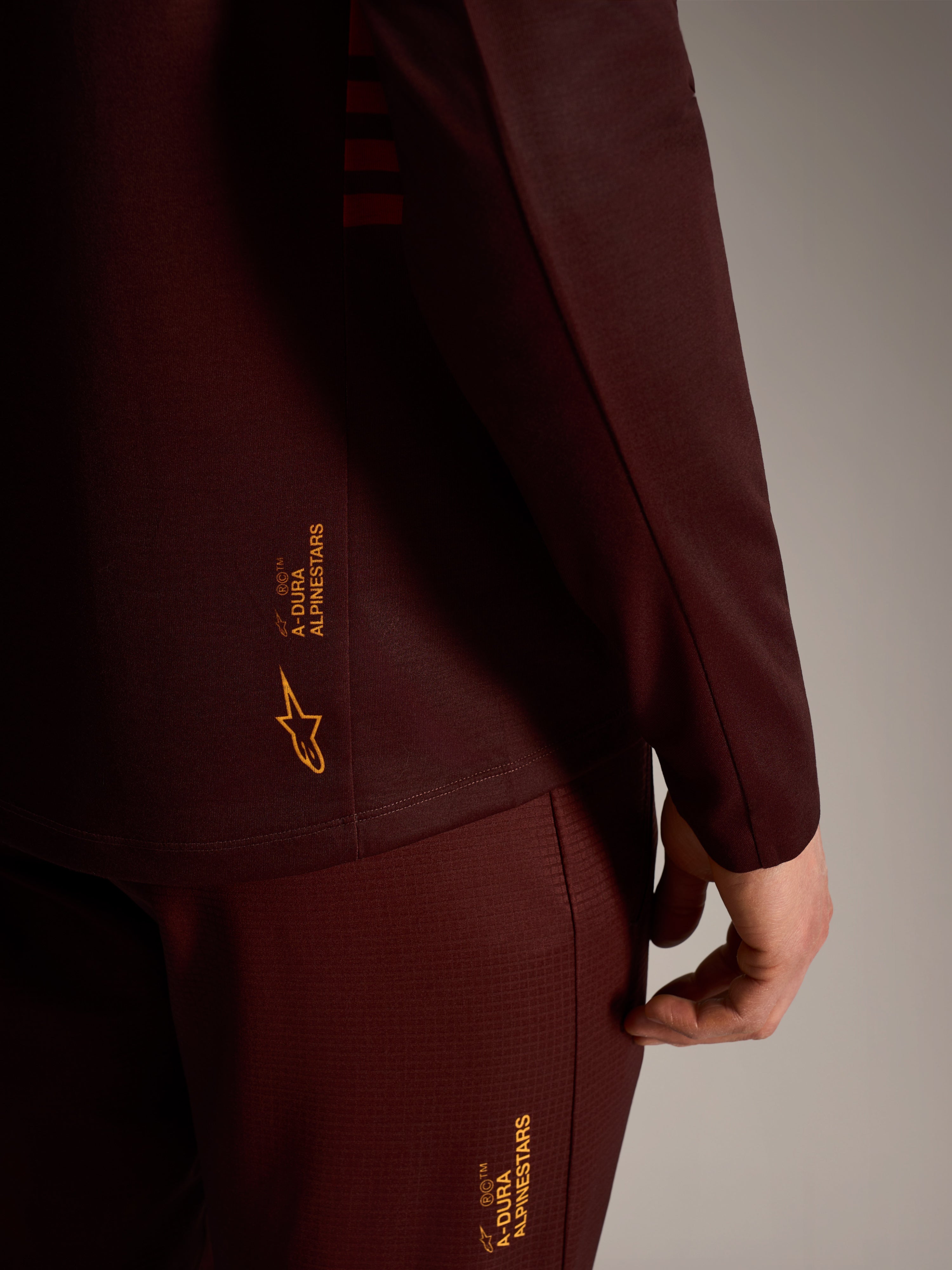 A-Dura Elite Langarmtrikot in Bordeaux, gelbes Alpinestars-Branding, technisches Funktionsgewebe für Trail-Performance.