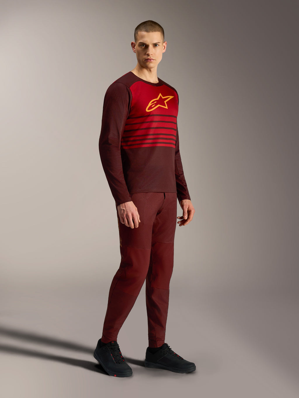 Alpinestars A-Dura Elite Trikot 2.0, bordeauxfarbenes Langarm-MTB-Jersey mit rotem Brustbereich und gelbem Logo.