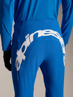 Alpinestars A-Supra Melt Hose und Trikot, blaue MTB-Ausrüstung, Rückansicht mit großem weißem Alpinestars-Schriftzug auf der Rückseite der Hose, passendes langärmeliges Trikot und schwarze Handschuhe