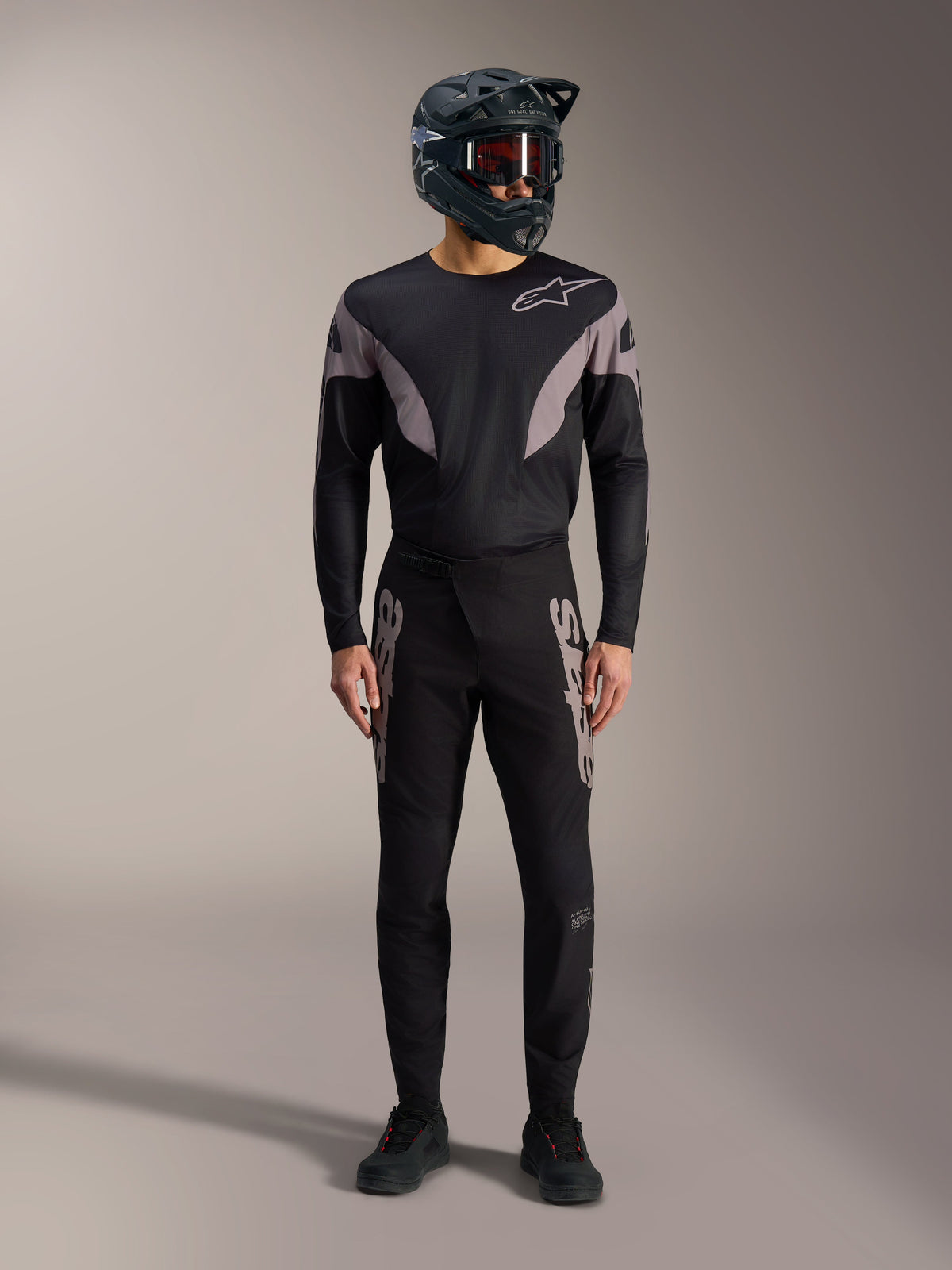 Schwarzes A-Supra Elite MTB-Kit, Langarmtrikot und Rennhose mit grauen Logos, Full-Face-Helm, Profi-Rennbekleidung