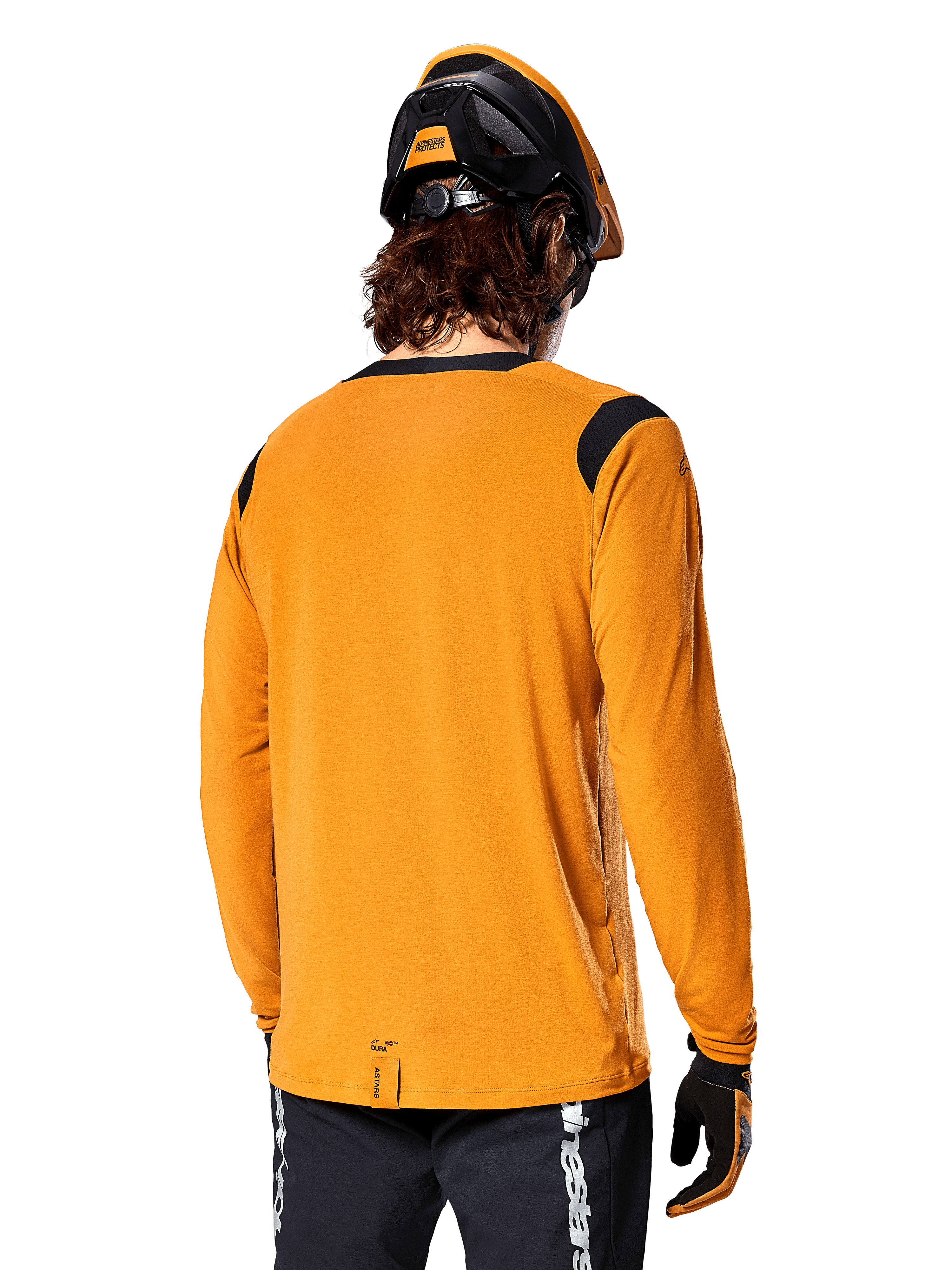 Alpinestars A-Dura Dri Wool Long Sleeve Jersey in Dark Gold, back view of a rider wearing a mountain bike helmet and gloves, featuring black mesh panels on the shoulders and a longer drop tail, technical cycling apparel for trail riding
