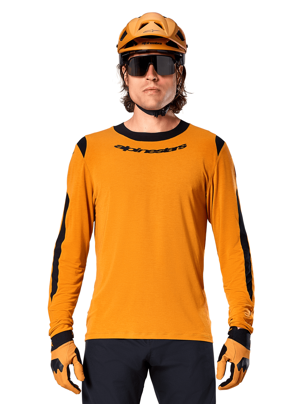 Male model wearing Alpinestars A-Dura Dri Wool Long Sleeve Jersey in Dark Gold, coordinated with a matching gold MTB helmet and gloves, black mesh panels on shoulders and sleeves, black Alpinestars wordmark on chest, dark sunglasses and pants, technical mountain bike apparel