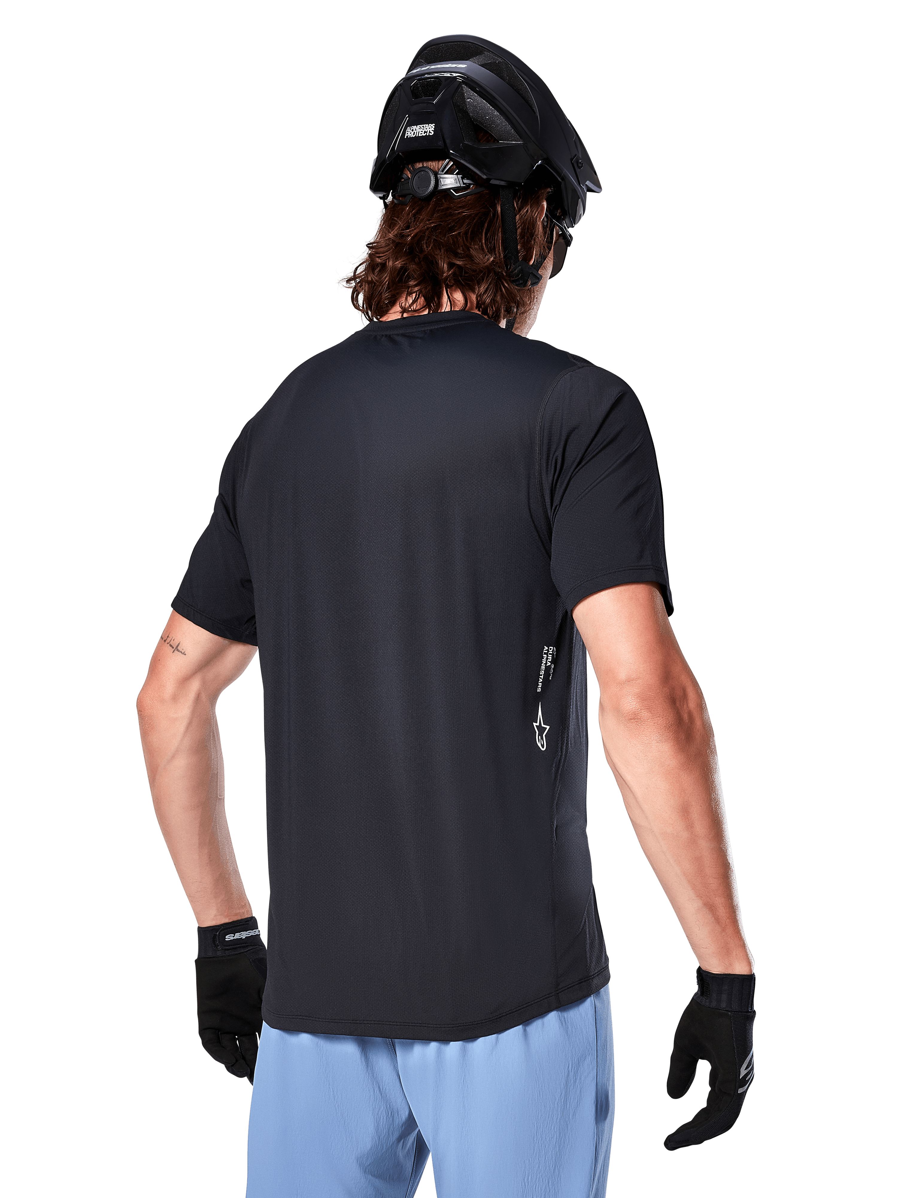 Alpinestars A-Dura Oscar Jersey, Short Sleeve cycling jersey, Black, rear view on rider, paired with light blue shorts and black MTB helmet, small white logo on the side, performance apparel for mountain biking