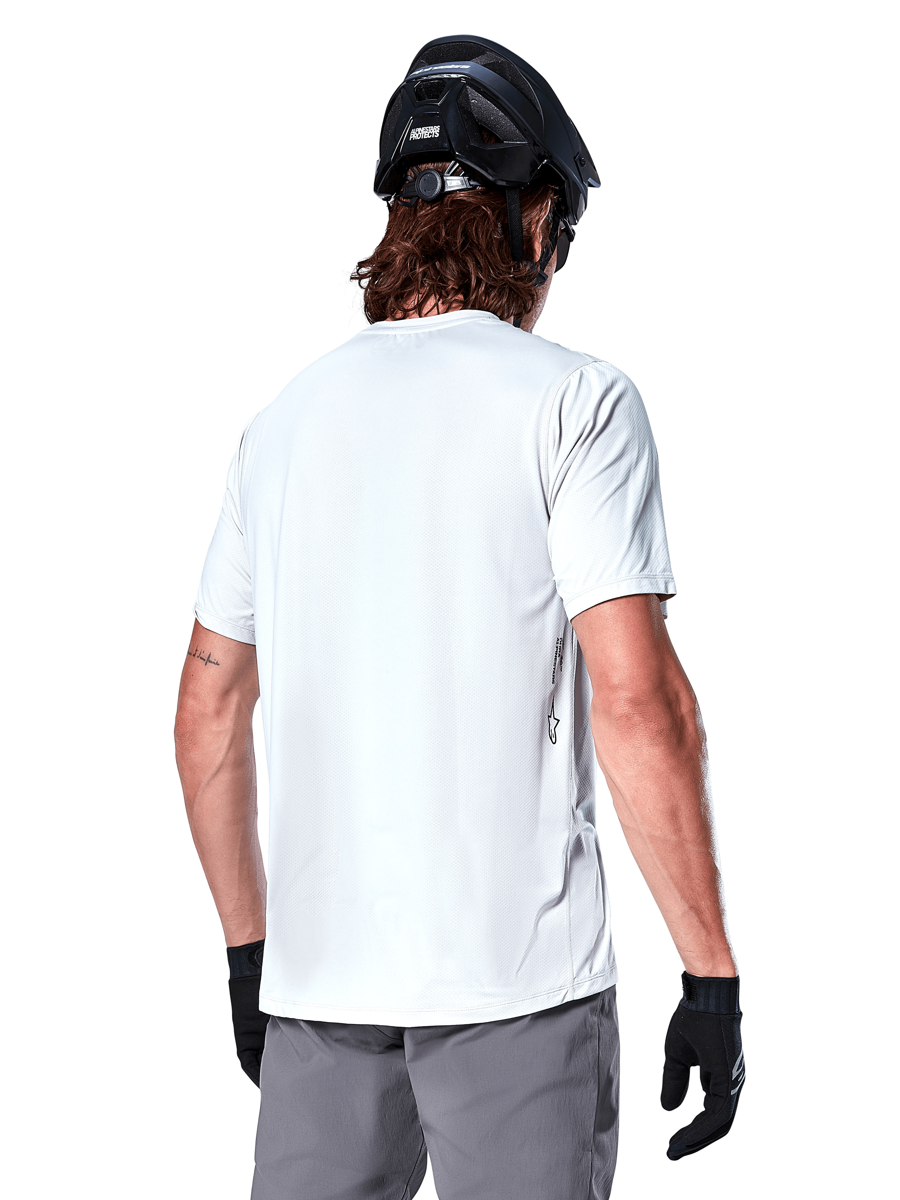 Alpinestars A-Dura Oscar Jersey, Short Sleeve MTB Jersey, White Dove, back view on a rider wearing a black cycling helmet, grey shorts, and black gloves, technical performance cycling gear