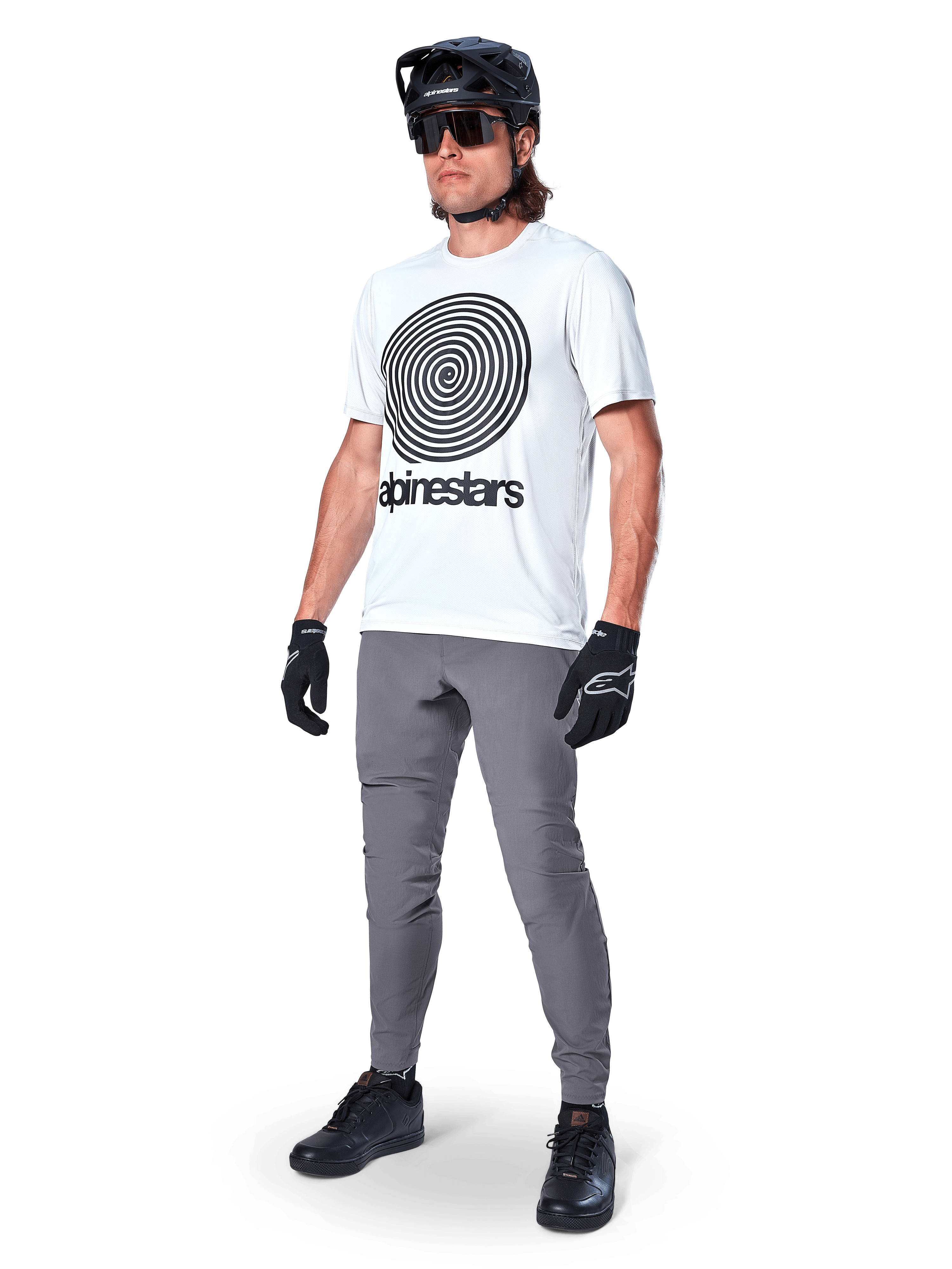 Alpinestars A-Dura Oscar Jersey - Short Sleeve, White Dove with large black spiral graphic, worn by a rider with grey MTB pants, black helmet, and gloves, performance cycling apparel for off-road riding