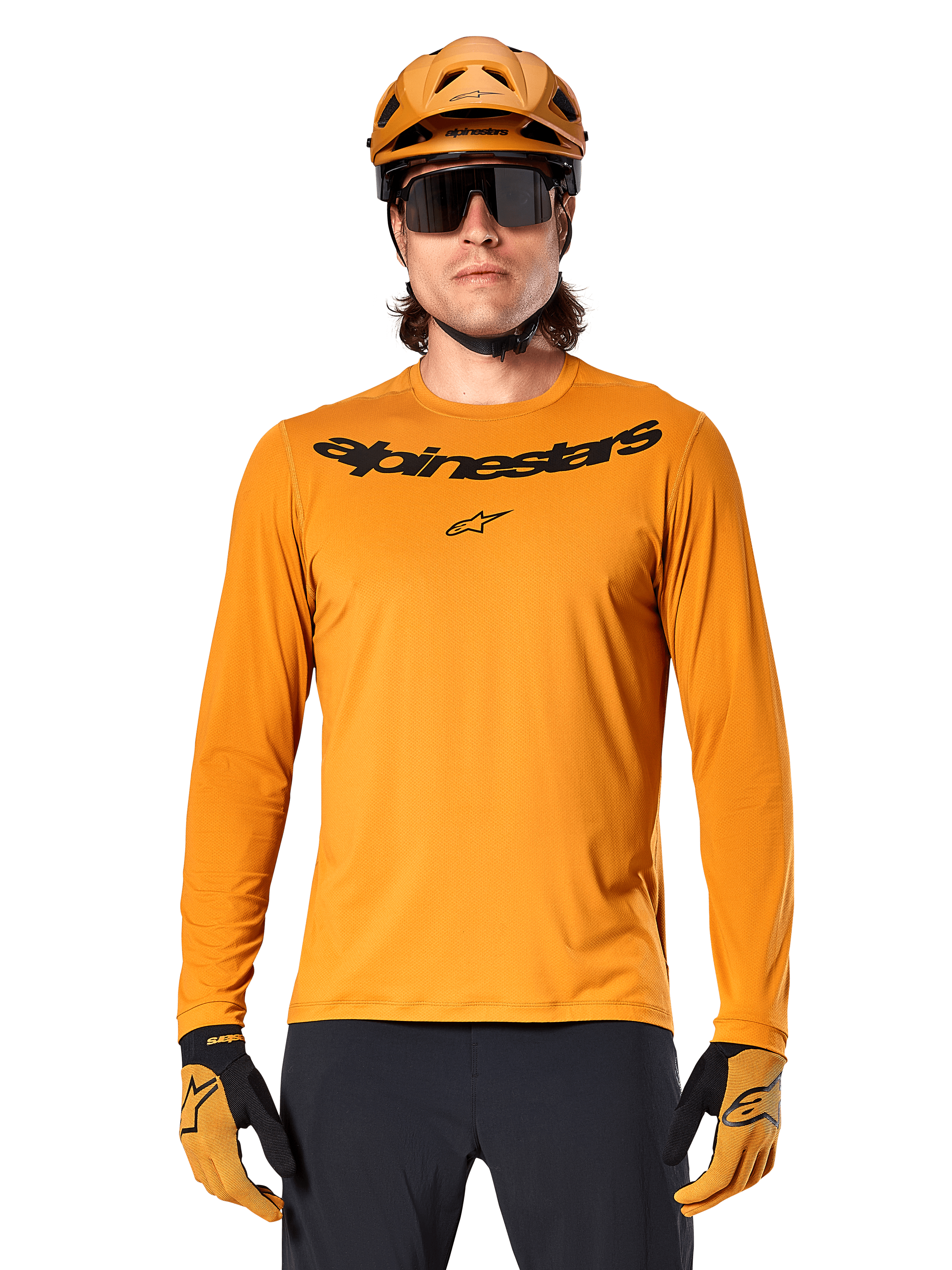 Alpinestars A-Dura Rocker Long Sleeve Jersey in Dark Gold, featuring a black wordmark logo on the chest, worn with a matching gold helmet and gloves for mountain bike performance.